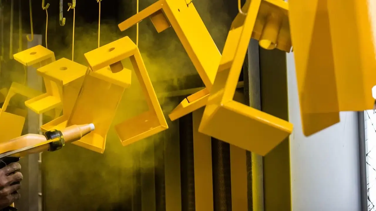 gold-coating Yellow powder coating being applied to fabricated metal brackets