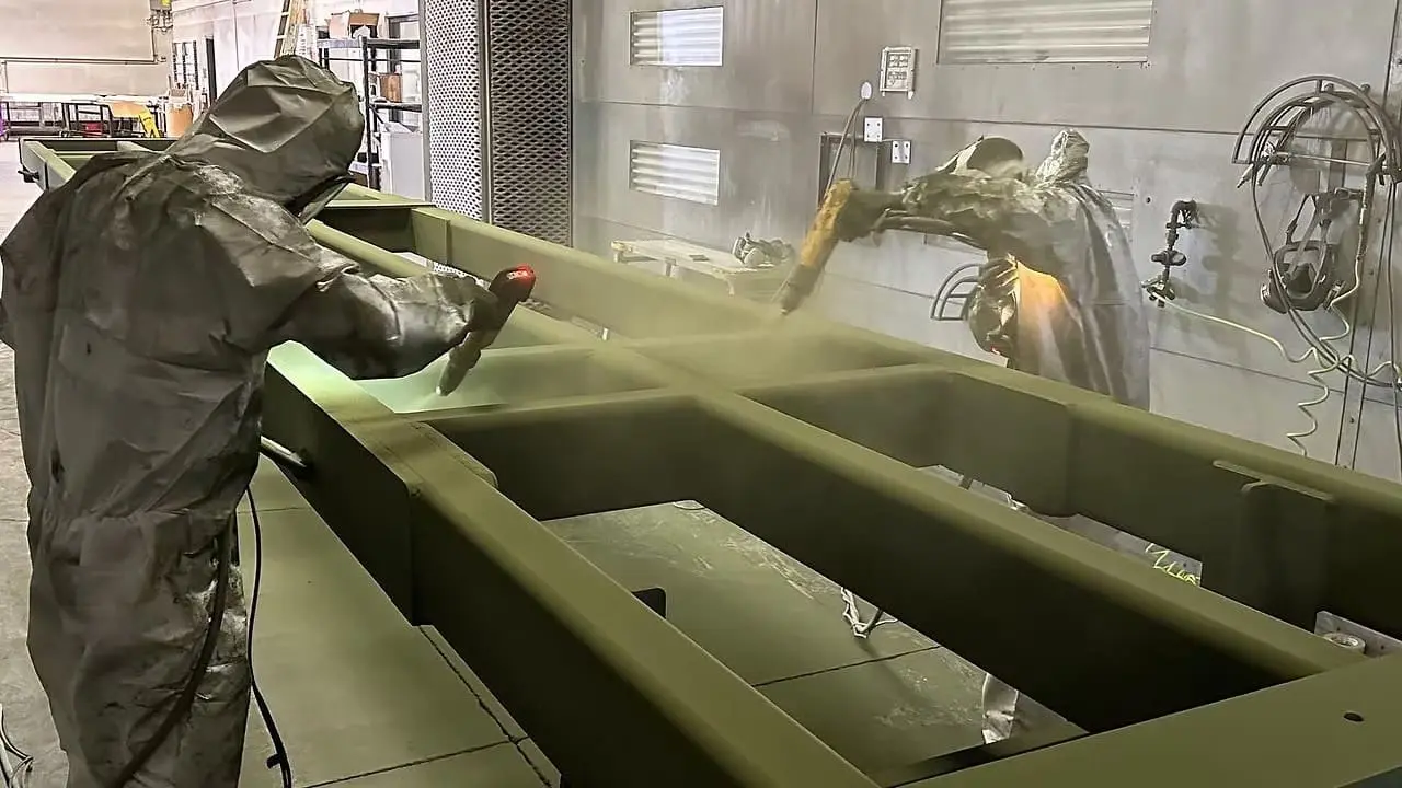 shop-frame Salt City Metal Coatings team powder-coating a large fabricated steel frame